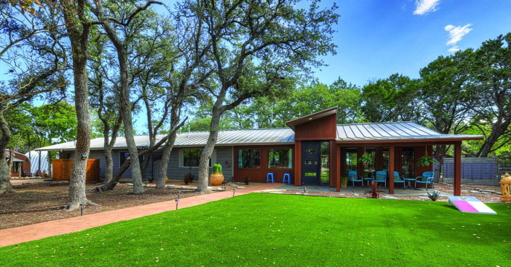 Luxury Terracotta Retreat vacation home exterior with a large wrap around porch in Wimberley, Texas.