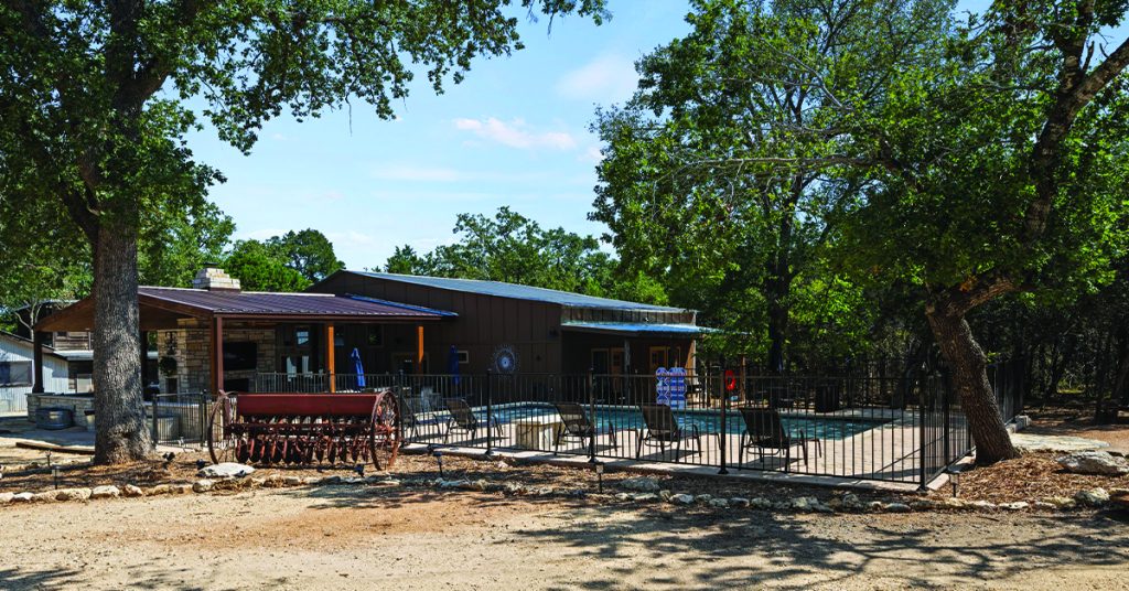 The secluded outdoor area of a vacation rental in the Texas Hill Country, showing the pool, sun chairs, and wooded setting for a relaxing December vacation.