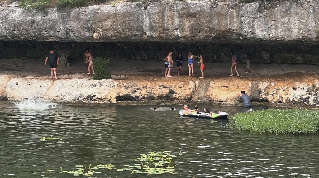 Visitors swimming and cliff jumping at Cypress Falls Swimming Hole.